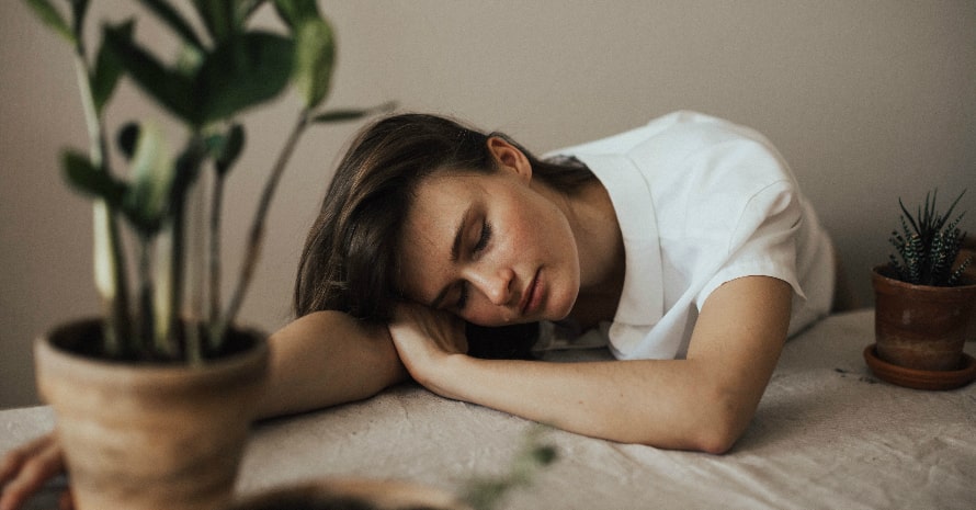 Woman wearing white collar top and sleeping on the table