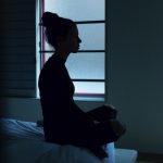 Woman-sitting-on-the-edge-of-bed-in-the-night