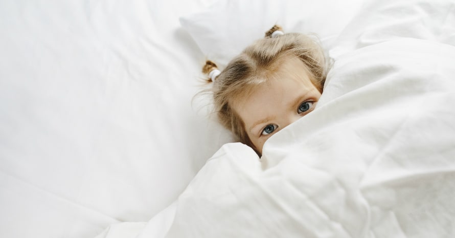 little baby girl lying in the bed with white sheets