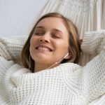 young smiling and dreaming girl lying and listening to music