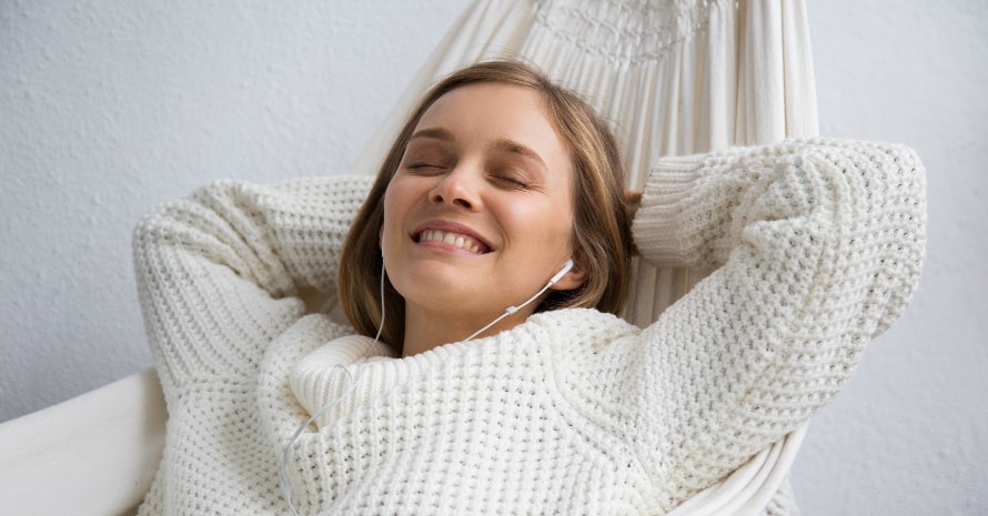young smiling and dreaming girl lying and listening to music