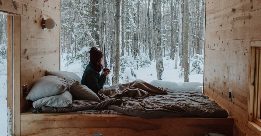 bed in front of the window with winter forest