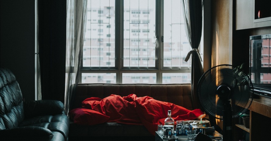 person sleeping on a couch with a fan in the room