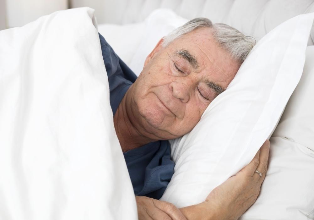An elderly man under a weighted blanket